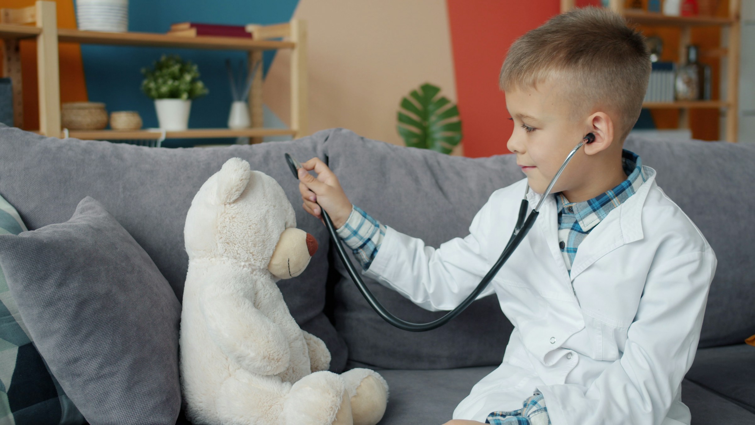 Child playing doctor with stethoscope and teddy bear